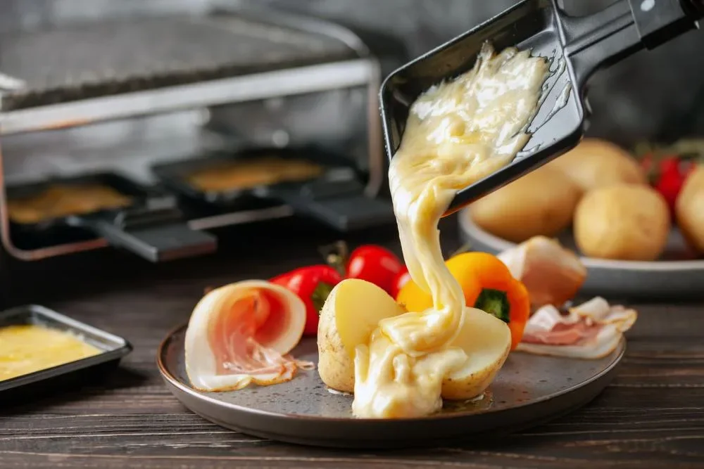 Raclette traditionnelle, fromage fondu coulant sur des pommes de terre et de la charcuterie