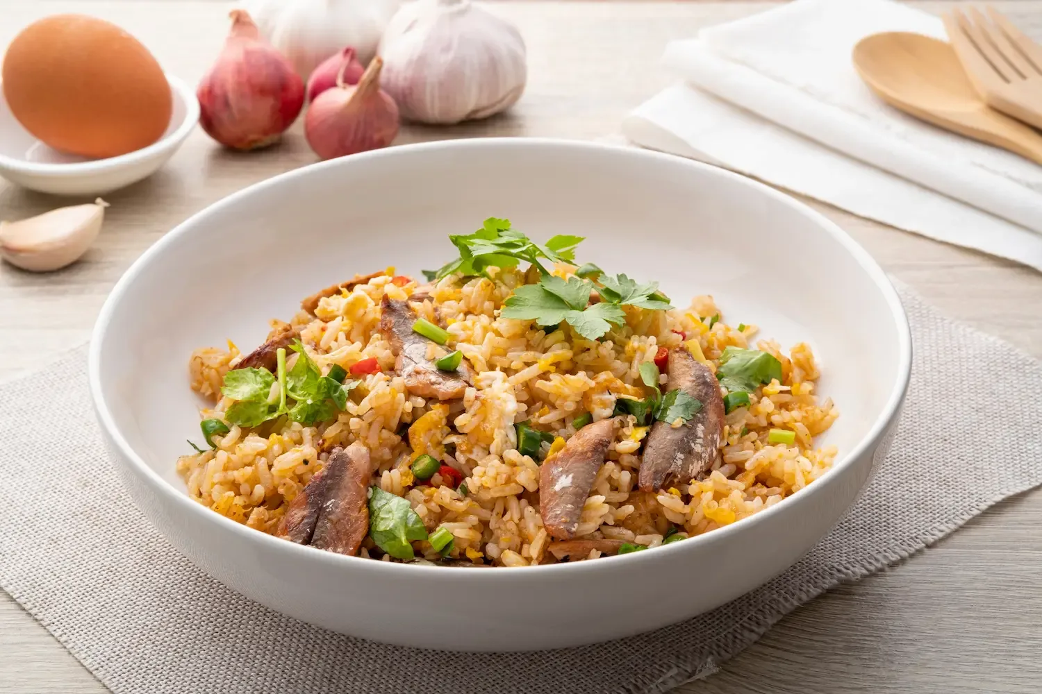 Un bol de riz garni, avec du persil, entouré d’échalotes, d’ail et d’œufs.